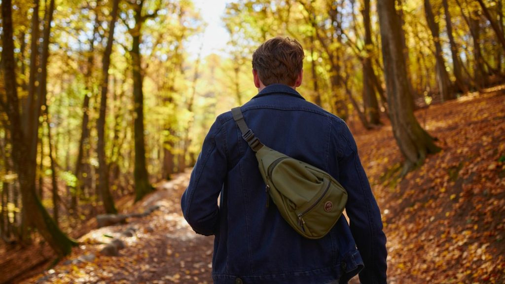 Randonneur sur un sentier forestier d’automne avec veste visible sans texte ni marque