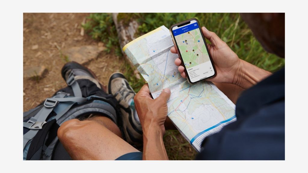 Randonneur consultant une carte GPS sur téléphone au départ d’un sentier