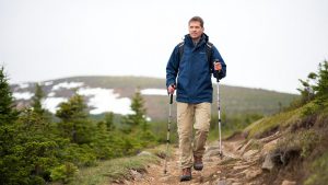 Randonneur adulte avec bâtons sur sentier naturel sans texte ni marque
