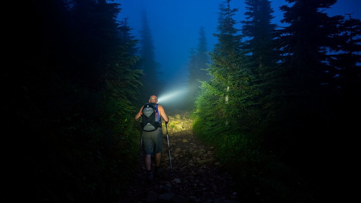 Randonneur de nuit avec lampe frontale sur sentier naturel sans texte ni marque