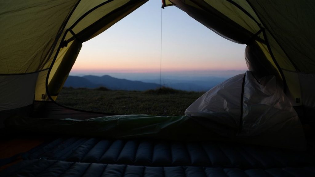 Matelas de bivouac installé dans une tente ouverte au lever du jour sans texte ni logo