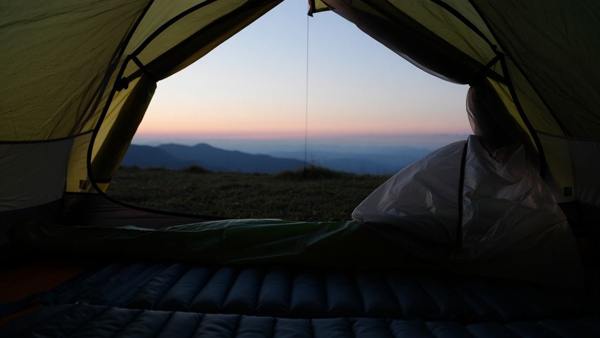 Matelas de bivouac installé dans une tente ouverte au lever du jour sans texte ni logo